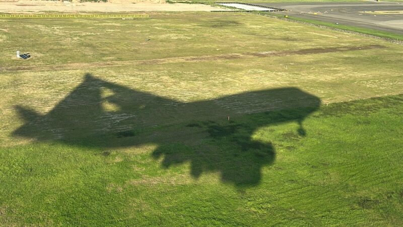 a shadow of an airplane on a grass field
