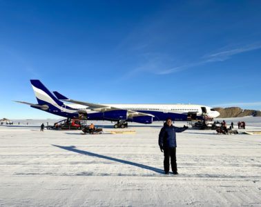 a man standing in the snow next to an airplane