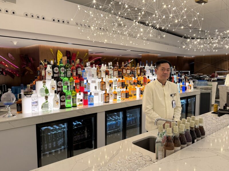 a man standing behind a bar with many bottles of alcohol