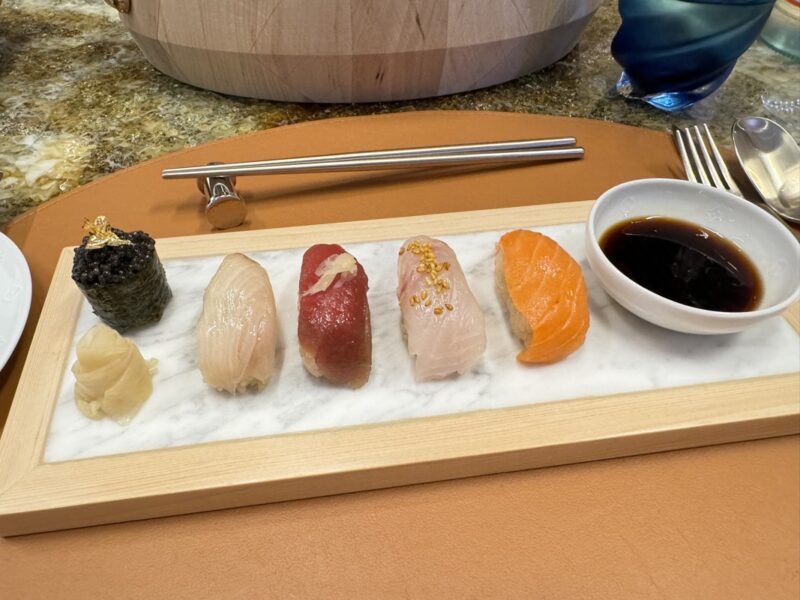 a plate of sushi with a bowl of sauce and chopsticks