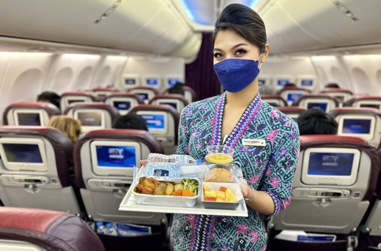 a woman wearing a face mask holding a tray of food