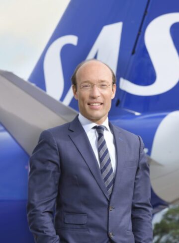 a man in a suit standing in front of a plane